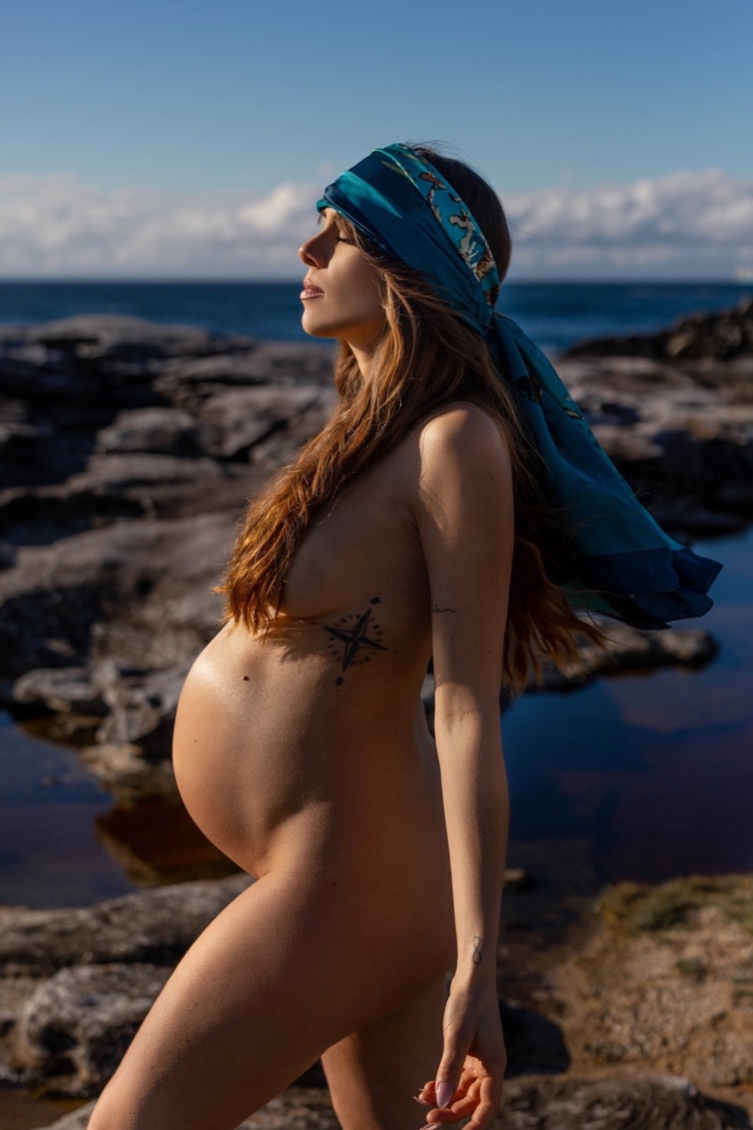 Pregnant woman in profile wearing a vivid blue silk scarf