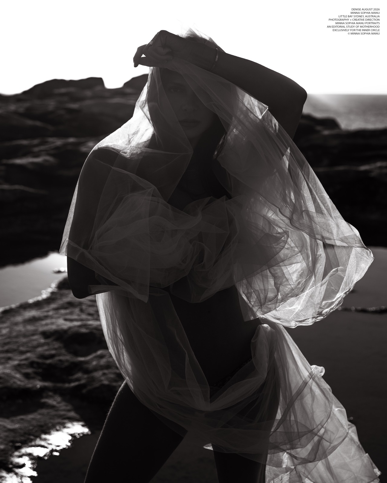 Black and white maternity portrait wrapped in translucent fabric