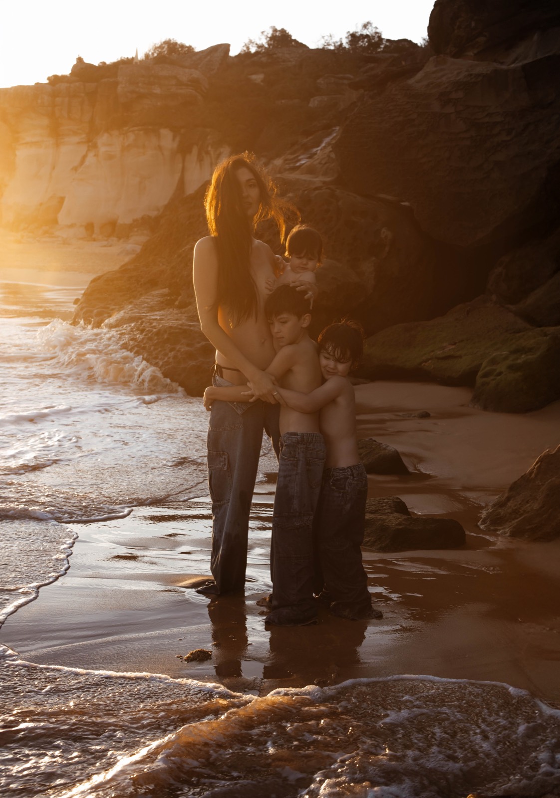 Mother standing with her four children in golden coastal light