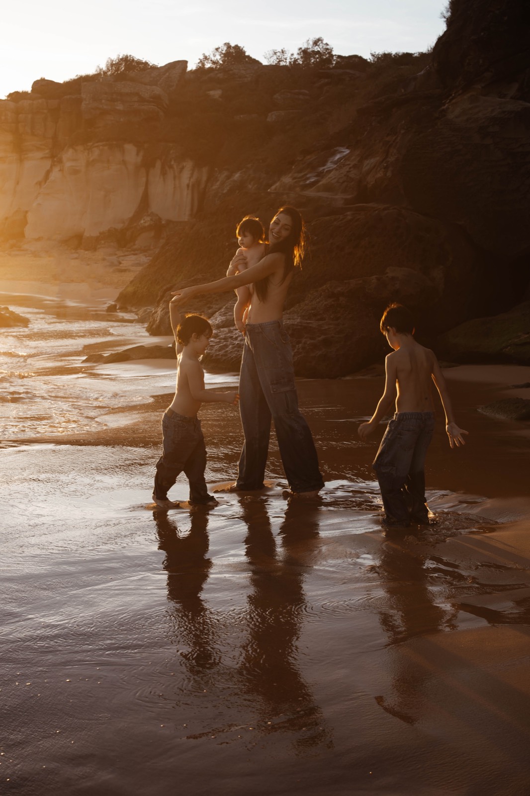Mother and children moving together through reflective tidal water