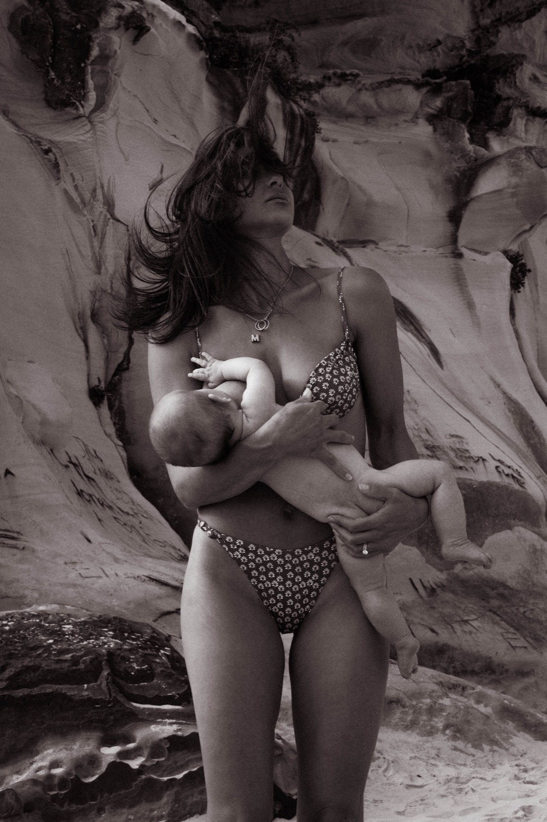 Mother cradling her baby against sculptural sandstone