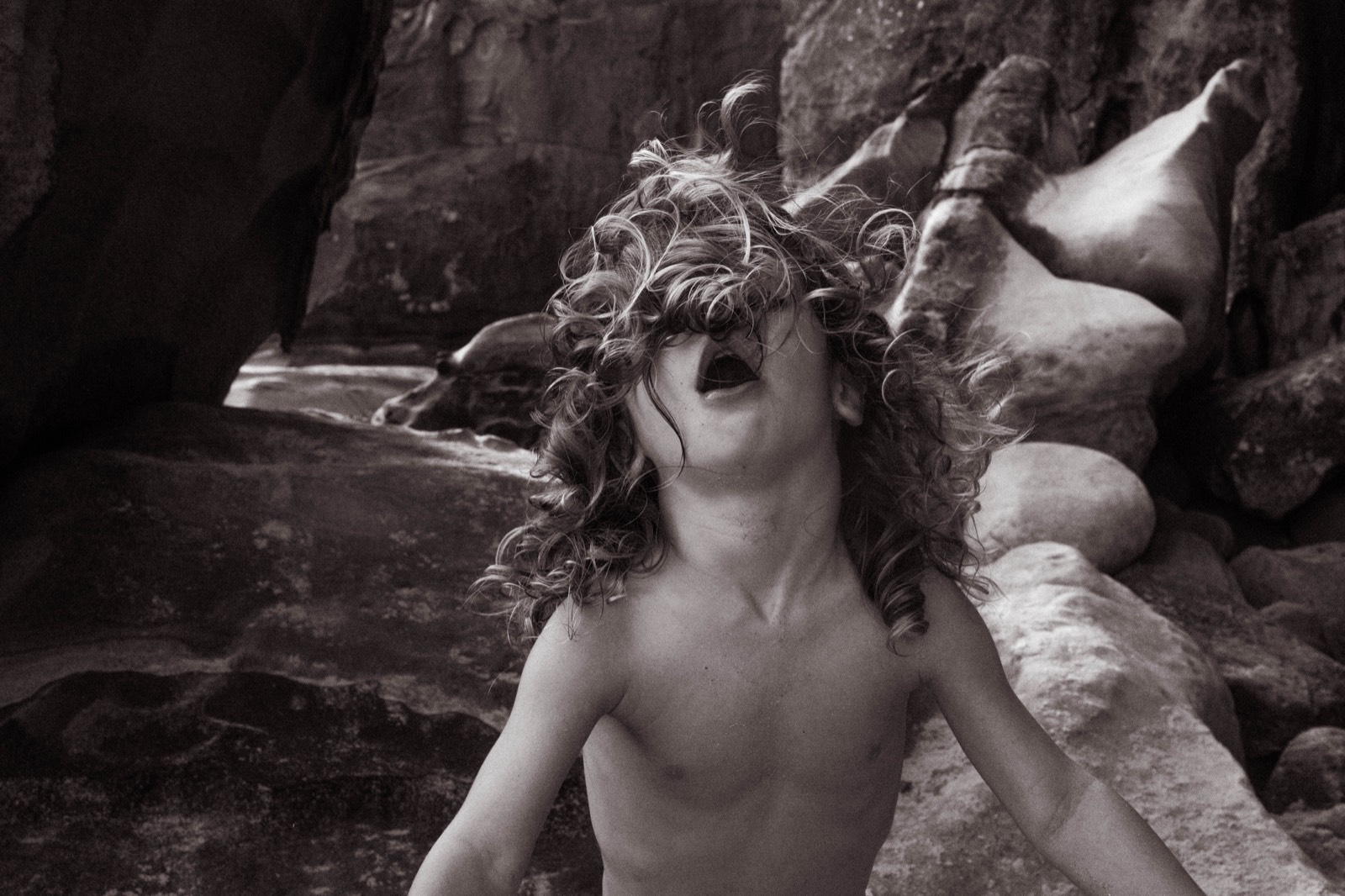 Child laughing freely among coastal rocks